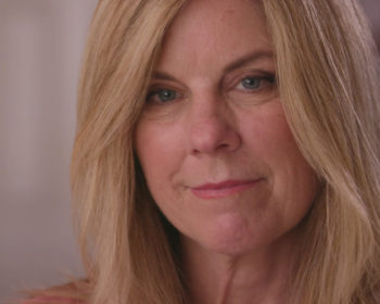 Cheryl, an older woman with blonde hair, smiles at the camera