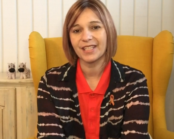 Regina, an older woman with brown hair, smiles at the camera