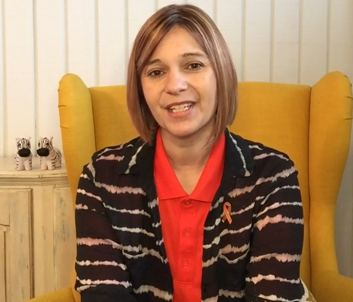 Regina, an older woman with brown hair, smiles at the camera