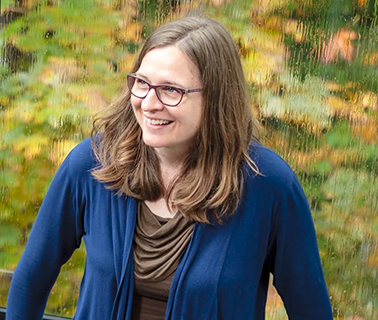 Ann, an woman with brown hair, smiles, looking away from the camera