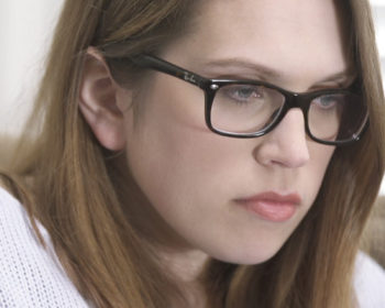 Tasia, a young adult woman with glasses does some writing at the table